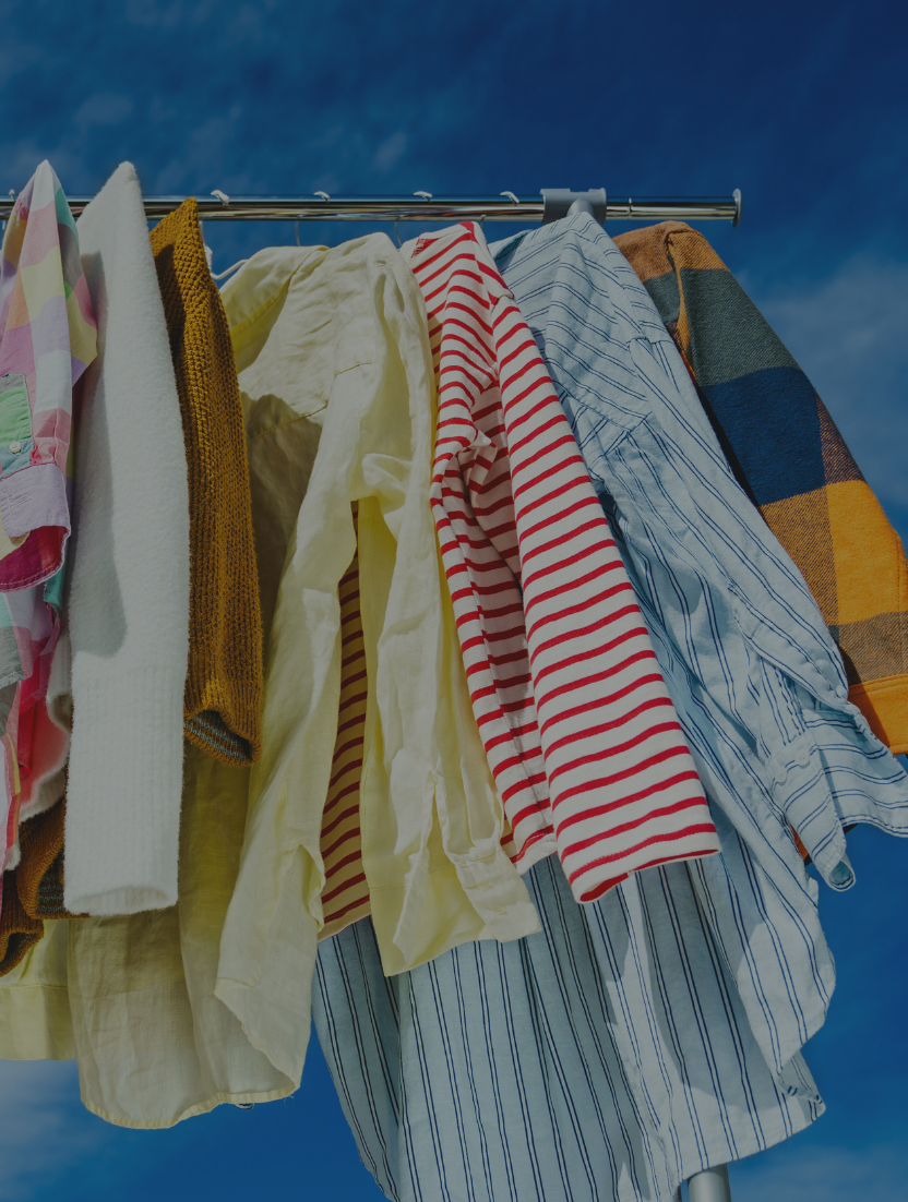 Clothing on a rack with bright blue sky in the background. Blog post explores key sustainability predictions for 2024 that could influence the future of fashion.